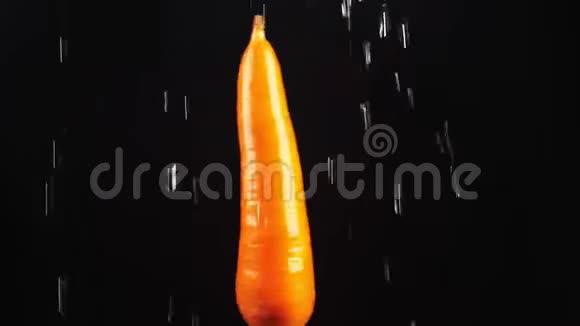 胡萝卜特写水滴落在黑色背景上旋转的苹果上超级慢动作视频的预览图