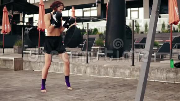 强壮的女拳击手戴手套带着一个袋子锻炼她用腿打了个包在外面健身女拳击手视频的预览图