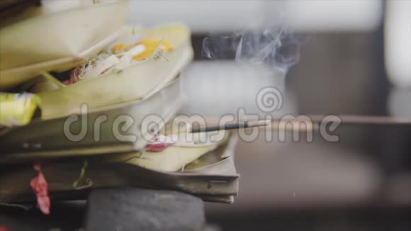 在巴厘岛传统的巴厘岛祭品用鲜花小棕榈叶金钱和芳香的木棍送给神灵视频的预览图