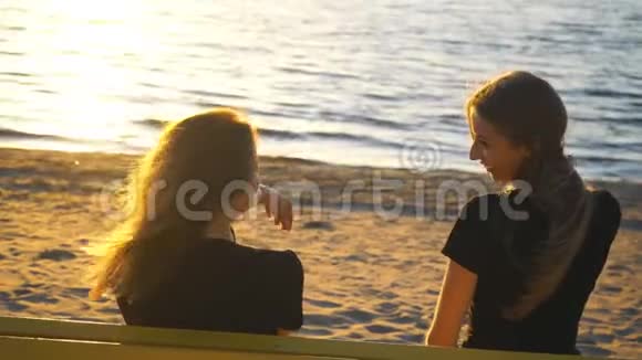 两个年轻女子坐在长凳上欣赏日落视频的预览图