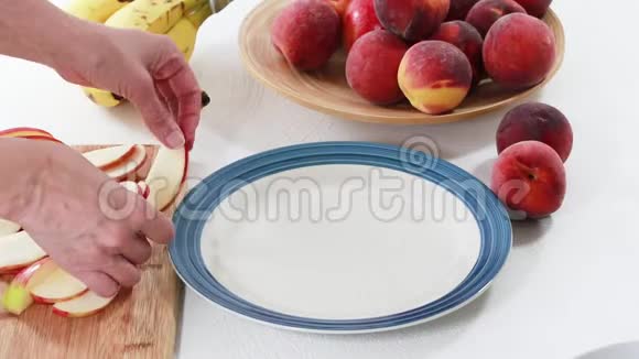 新鲜水果盘一步一步苹果桃子和香蕉片放在盘子里贴在白色背景上女人的手视频的预览图