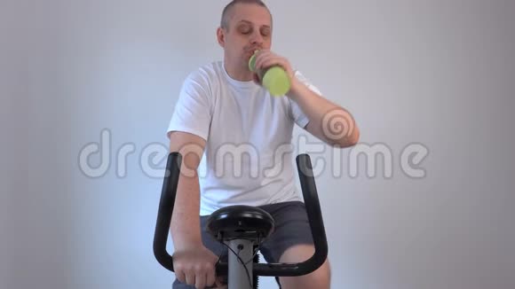 一个人从瓶子里喝酒用运动自行车视频的预览图