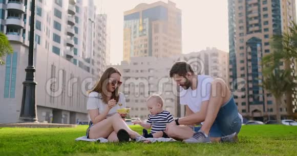一家人坐在城里的草地上和一个小孩子一起笑视频的预览图