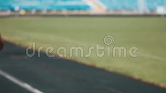 一个穿着运动服的强壮女孩在体育场奔跑的肖像美丽的女孩在体育场奔跑倾听视频的预览图