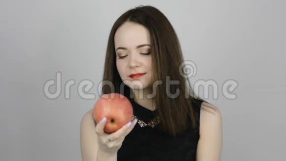 迷人的年轻女人吃着粉红色的苹果微笑着视频的预览图