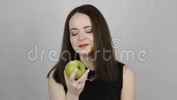迷人的年轻女人吃着绿色的苹果微笑着视频的预览图