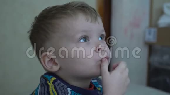 一个两岁的男孩正在一个黑暗的房间里看电视视频的预览图
