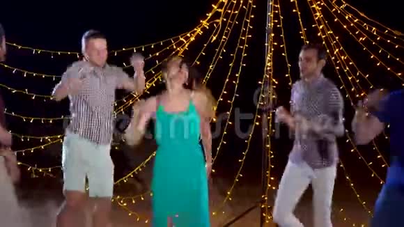 欢乐的人们在夜晚的海滩派对上跳舞视频的预览图