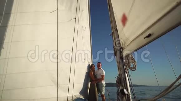 镜头移向年轻情侣拥抱在帆船上视频的预览图