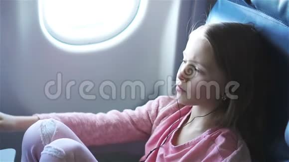 可爱的小女孩乘飞机旅行可爱的孩子在飞机窗口附近看电影流动人口视频的预览图