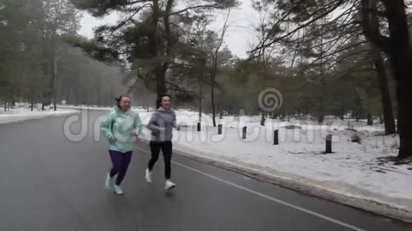 快乐的年长和年轻的高加索女人在冬天的雪地公园里奔跑交谈和微笑慢动作视频的预览图