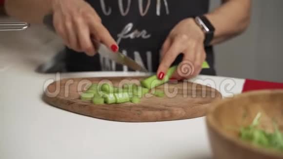 女人在切菜板上切芹菜做自制蔬菜沙拉视频的预览图