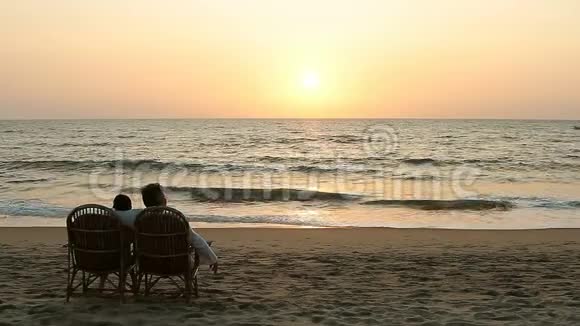 可爱的情侣坐在扶手椅上享受日落视频的预览图