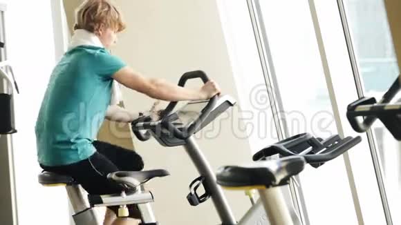 一个年轻人在健身房骑健身自行车的加速镜头视频的预览图
