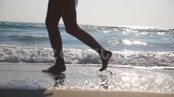 靠近雌性的脚在潮湿的沙滩和海水上奔跑背景是波浪年轻女子的腿视频的预览图