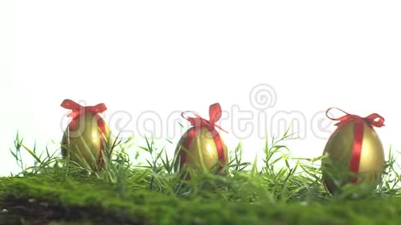 在绿草上用红丝带系着金色颜料的鸡蛋视频的预览图