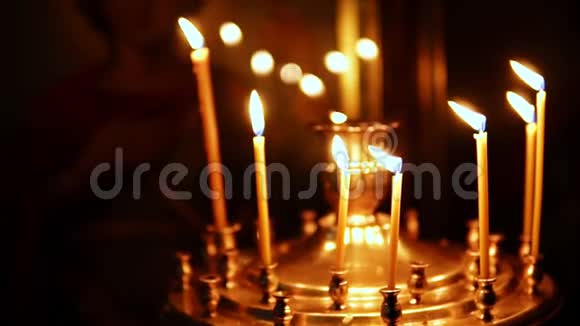 在宗教偶像的背景下在教堂烛台上点燃蜡烛视频的预览图