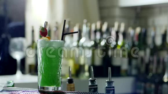 带塑料吸管和浆果的绿色鸡尾酒放在酒吧柜台上烟雾弥漫视频的预览图
