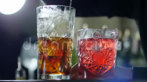 长酒吧汤匙把干邑里的冰混在玻璃里放在没有聚焦的背景上视频的预览图
