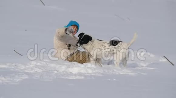 男孩少年在雪地里和狗玩得很开心视频的预览图