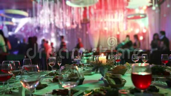 有眼镜和蜡烛的餐厅的宴会桌人们在桌子的背景下跳舞宴会桌桌视频的预览图