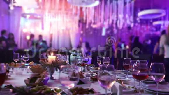 有眼镜和蜡烛的餐厅的宴会桌人们在桌子的背景下跳舞宴会桌桌视频的预览图