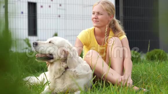 对宠物的爱一个年轻的金发女人和她的狗在草地上休息视频的预览图