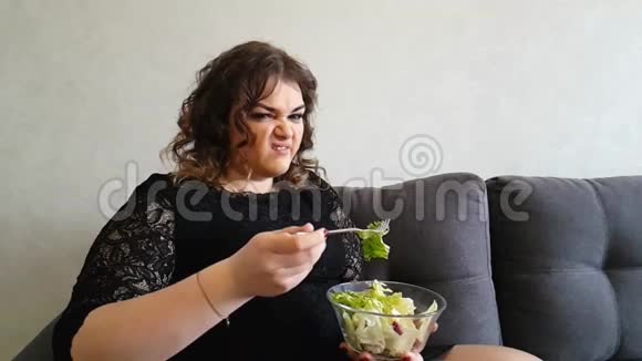 美丽的女孩吃沙拉沙发饥饿厌恶情感开胃视频的预览图