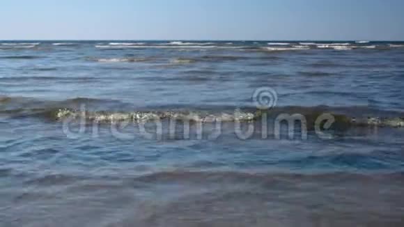 沙滩上从左到右在海边的浅水上行走的人视频的预览图