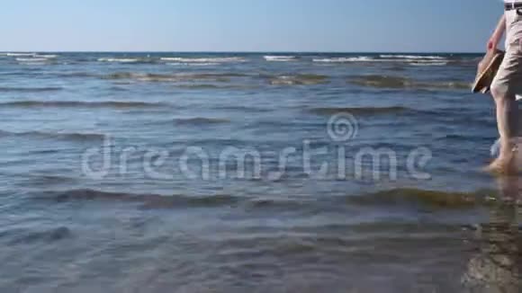 人在沙滩上从右到左在海边的浅水中行走视频的预览图