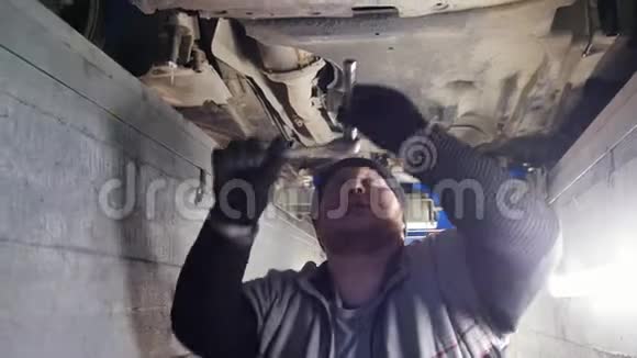 汽车服务一个强壮的机械师站在检查坑里用工具工作视频的预览图