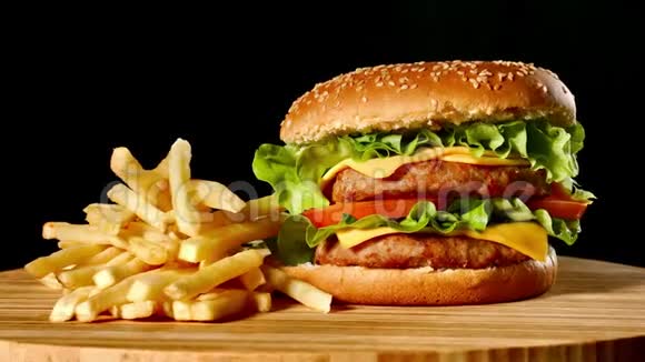 在黑色背景的木桌上制作牛肉汉堡和炸薯条视频的预览图