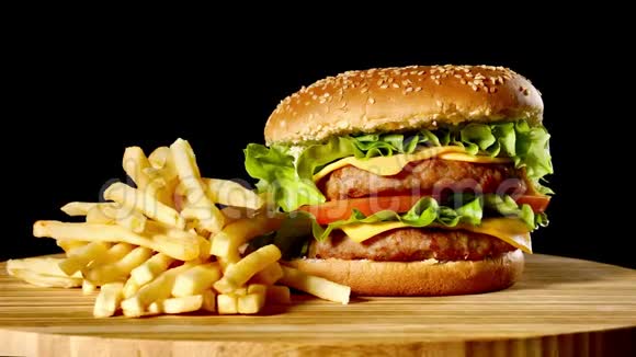 在黑色背景的木桌上制作牛肉汉堡和炸薯条视频的预览图