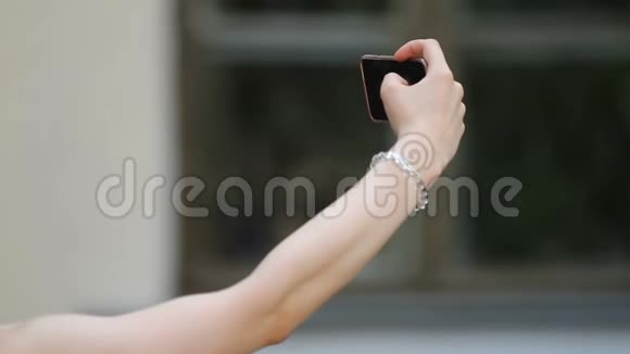 年轻女性在智能手机上自拍的手在社交网络上分享照片视频的预览图