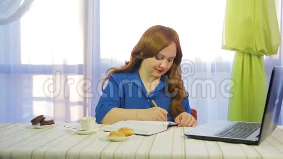 一个棕色头发的女人在一张桌子上的咖啡馆里工作手提电脑和喝咖啡视频的预览图
