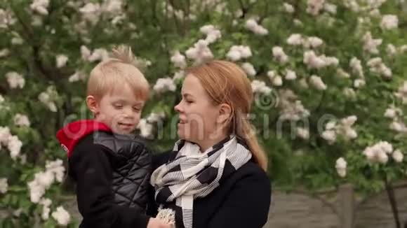 母亲和儿子在春天盛开的公园里散步视频的预览图