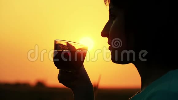 夕阳西下的城市剪影中美丽的女孩在窗边缓慢地喝着咖啡视频的预览图