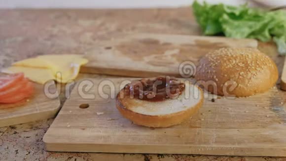 男人用面包沙司西红柿黄瓜肉排奶酪沙拉沙司培根做汉堡特写手高速视频的预览图