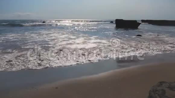 阳光反射在灰色沙滩上的泡沫波上视频的预览图