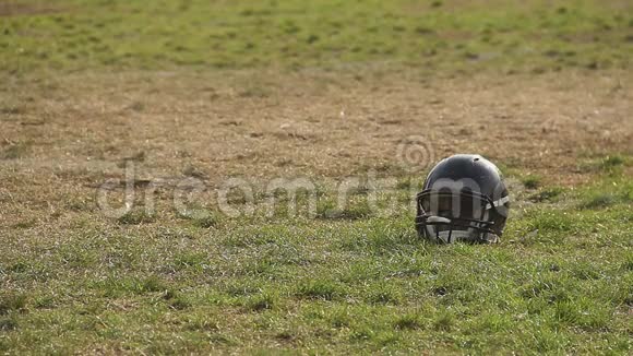 对运动失去兴趣被遗忘的足球头盔躺在球场上视频的预览图
