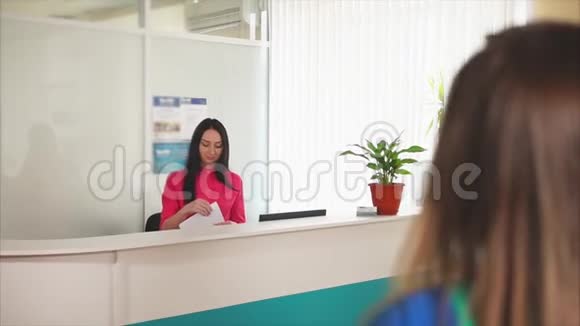 一位友好的年轻女管理人员在牙科诊所与一位客人微笑视频的预览图