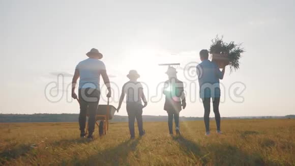 家庭农民在日落时分沿着田野散步带着新鲜蔬菜和农具的盒子有机有机视频的预览图