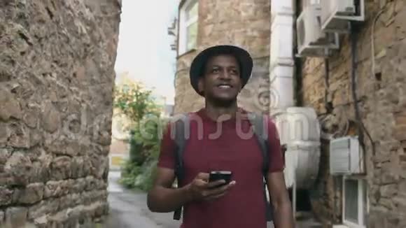 快乐的非裔美国学生步行和使用智能手机应用程序户外视频的预览图