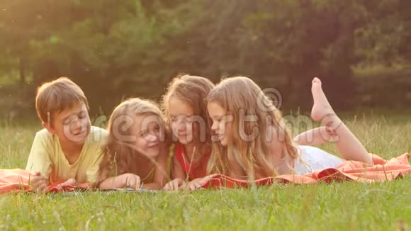 男孩和女孩在花园里读一本书躺在毯子上美丽的夏日关门视频的预览图