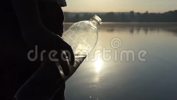 夕阳西下年轻人举起一个塑料瓶喝水视频的预览图