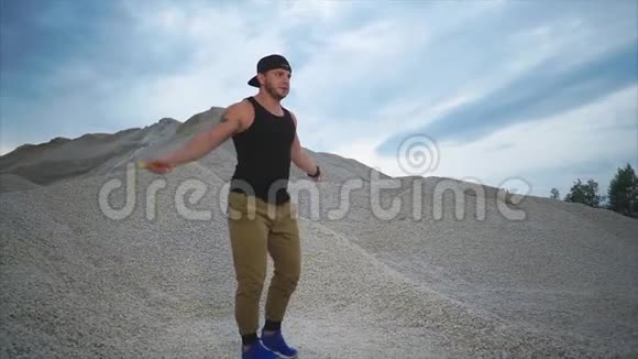 一个有石头背景的夏天年轻人在大自然中积极地跳绳视频的预览图