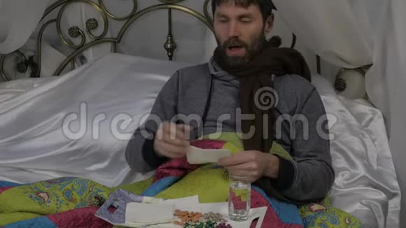 一个病人躺在床上脖子上围着一条温暖的围巾咳嗽着喝着一片药丸慢动作视频的预览图