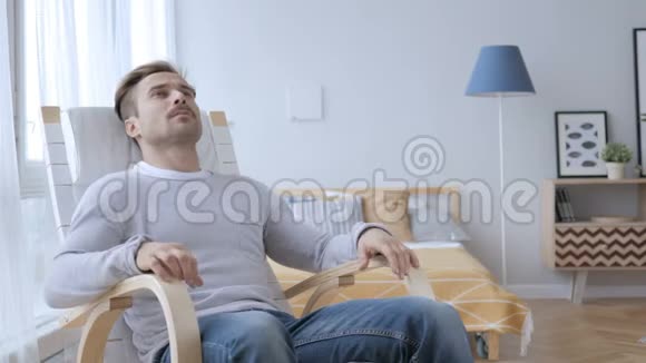 在卧室里离开放松椅的成年男子视频的预览图