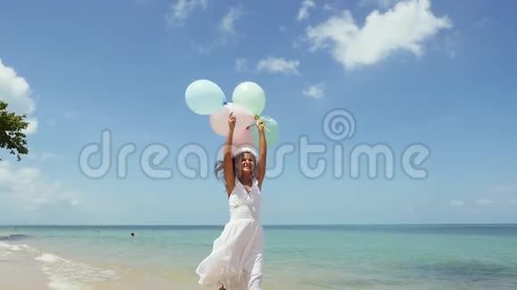 快乐的女孩在海滩上奔跑手里拿着气球在旋转慢动作概念幸福自由视频的预览图