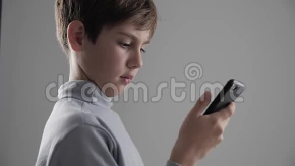 青少年1112岁男孩在白色背景下使用智能手机的肖像视频的预览图